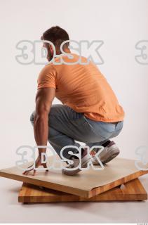 Kneeling pose orange thsirt light blue jeans of bodybuilder Harold…